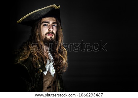 Portrait of a medieval bearded pirate on black background.