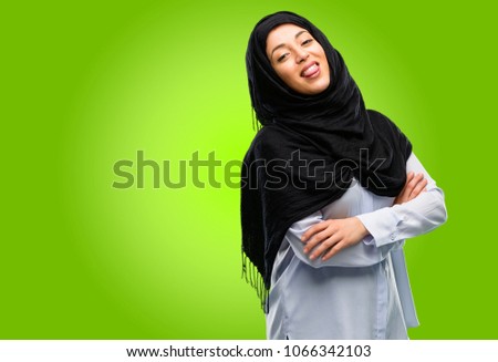 Young arab woman wearing hijab sticking out tongue at camera at sign of disobedience, protest and disrespect