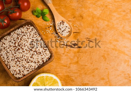 Dry mixture of quinoa grains on wooden background with tomatoes and lemon. Selective focus.