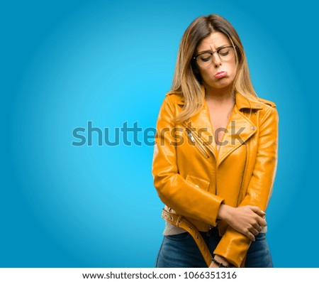 Beautiful young woman with sad and upset expression, unhappy, blue background