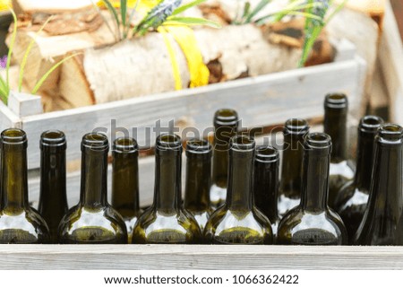 Empty wine bottles stand in a row in a wooden drawer outdoor