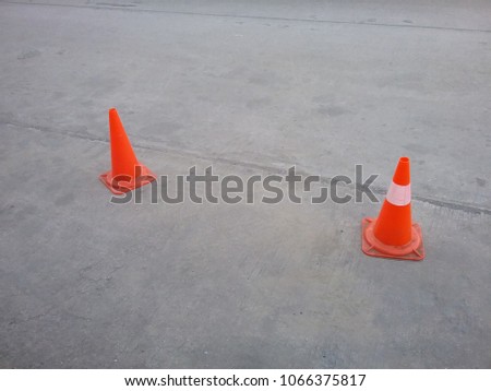 two traffic cones on the street, one all orange, one orange with a white stripe line