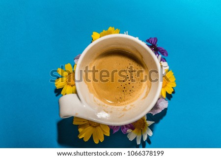 A cup of espresso surrounded by a circle of flowers