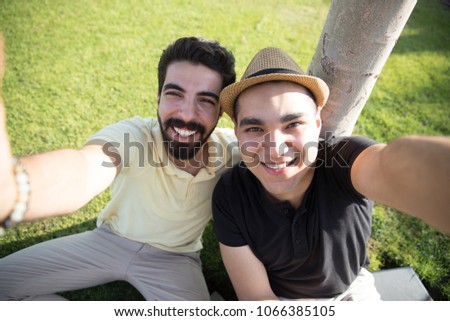 Two friends raising the camera up took a selfie smiling.