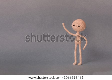 A toy man on a gray background with copy space. Cute amigurumi. Presentation PowerPoint or Keynote. Motivational phrase. Man with one hand shows up object