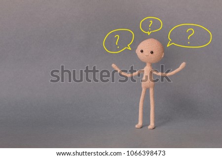 A toy man on a gray background with copy space. Presentation PowerPoint or Keynote. Motivational phrase. A sketch is drawn on top of the photo.The man and the many questions above the head