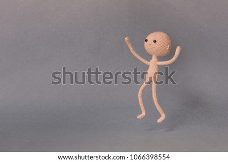 A toy man on a gray background with copy space. Cute amigurumi. Presentation PowerPoint or Keynote. Motivational phrase. The man jumps with open arms