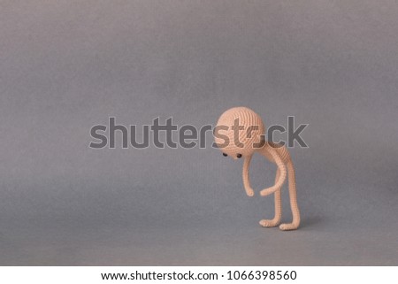 A toy man on a gray background with copy space. Cute amigurumi. Presentation PowerPoint or Keynote. Motivational phrase. Man leaned against the earth and holds the object.