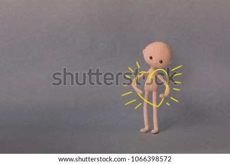 A toy man on a gray background with copy space. Presentation PowerPoint or Keynote. Motivational phrase. A sketch is drawn on top of the photo.Man holding a big heart