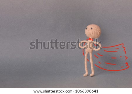 A toy man on a gray background with copy space. Presentation PowerPoint or Keynote. Motivational phrase. A sketch is drawn on top of the photo.Man with red cloak in the pose of a superhero