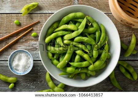 Fresh steamed edamame sprinkled with sea salt on a rustic tabletop. Royalty-Free Stock Photo #1066413857