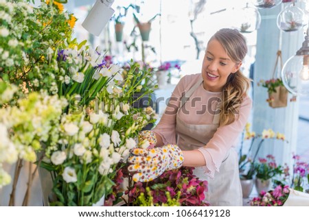 Young shop owner. Beautiful young florist in flower shop. Female florist touching flower bouquet in the flower shop. Professional florist working in flower shop.
