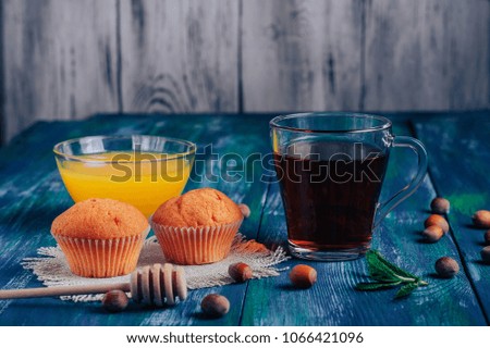  tea with honey, mint and cupcakes on blue rustic background, with nuts and cinnamon, selective focus. Tea party. View from above