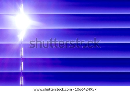 blue horizontal blinds on the window create a rhythm, through the intervals the light passes through