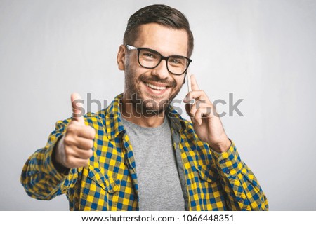 Happy handsome man showing thumbs up on the grey background. Using phone. 
