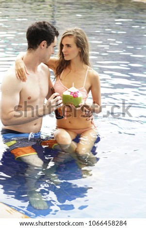 The lover relax on holiday in swimming pool. Loving couple spending vacation on tropical resort swimming pool.Newlyweds honeymoon on seaside.Couple in true love.Flirting and showing emotions.