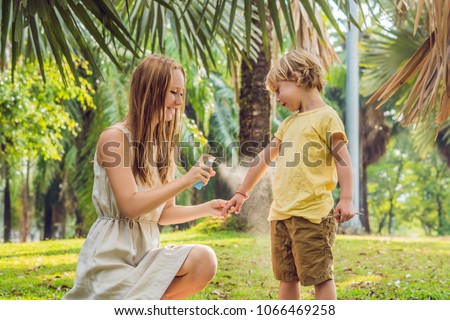 Mom and son use mosquito spray.Spraying insect repellent on skin outdoor Royalty-Free Stock Photo #1066469258