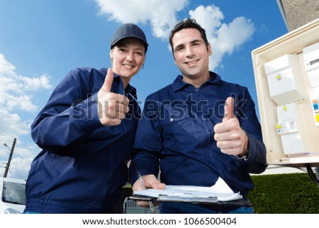 male and female technicians holding thumbs up by electric meter