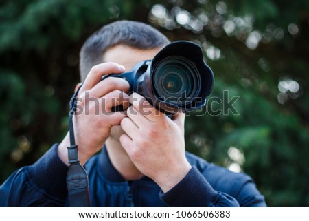 A young man with a camera takes pictures of nature