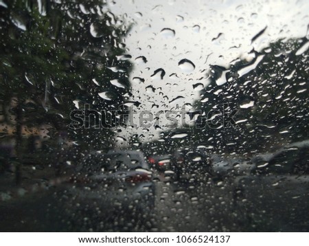The view of the street through the windshield while it rains.