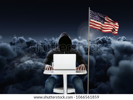 Hacker working on laptop close to the american flag with cloudy background