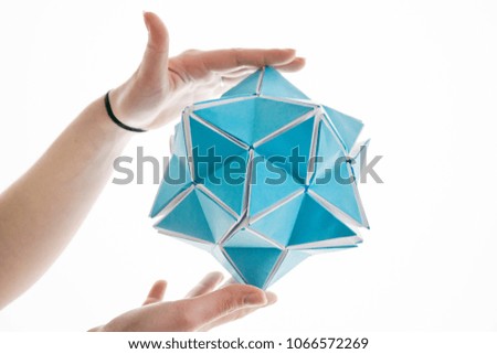 Hands holding paper poly made star shape on white background. Futuristic creative polygon origami figure.