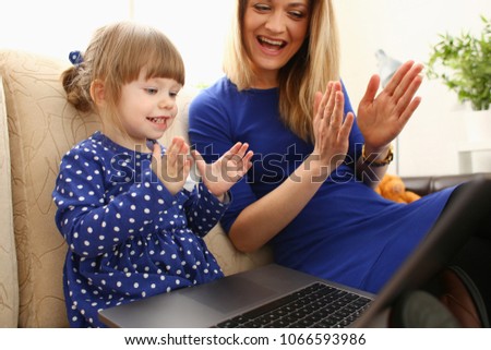 Cute little girl on couch with mom use laptop pc for chat with her dad away on business portrait. Point finger hand in display social web network bank mortgage credit wireless ip telephony concept