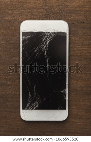 Smartphone with broken screen on wooden table, copy space, top view. Repairing services concept