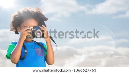 Boy with camera against sky with flare