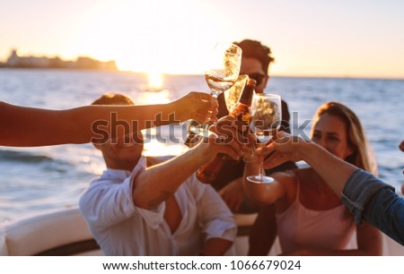 Sunset boat party with young people toasting drinks. Group of men and women having a boat party. Royalty-Free Stock Photo #1066679024