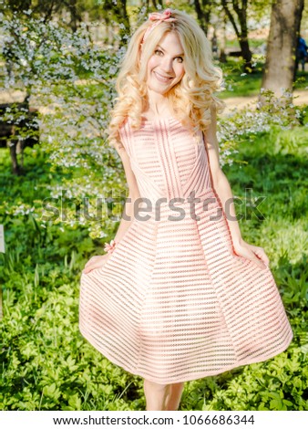 blonde in a pink summer dress on a background of flowering garden