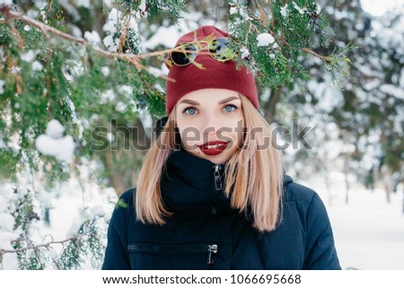 winter, christmas, emotions, people, lifestyle and beauty concept- Christmas girl outdoor portrait. Winter woman blowing snow in a park. Flying Snowflakes. Sunny day. Good mood