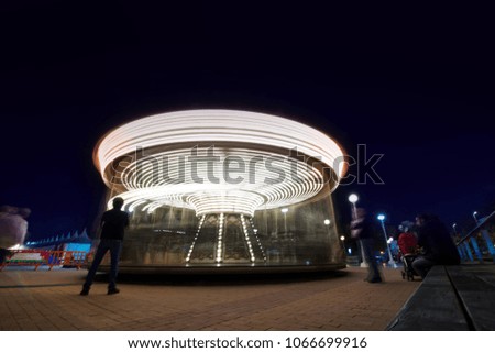 Abstract, long exposure shot of spinning Children's vintage Carousel at an amusement park in the evening and night illumination. Beautiful, bright carousel in Alicante, Spain