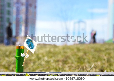humanized figure made of AA battery holds in hands poster with the the globe symbol of the earth day. Holiday concept. Copy space for text.