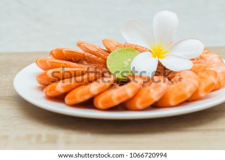 Texture of Boiled Shrimp in a shell with lime and flower Plumeria on a plate on a table