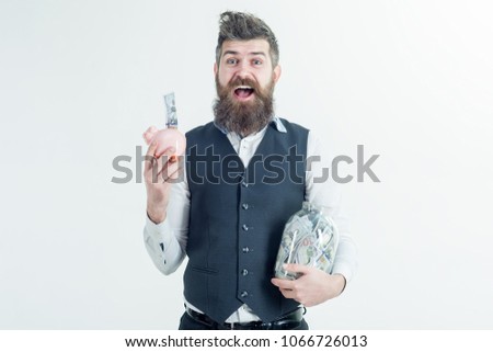 Happy smiling bearded man holds jar with money and piggybank. Finance. Bank advertising. Piggybank. Bearded hipster holds piggy-bank. Banknotes. Saving money concept.