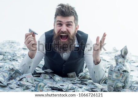 Business man, millionaire, billionaire, bearded man with many banknote. Business man lying in banknotes. Bearded man holds plane from bankote. Bank advertising. Travels.