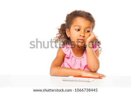 Education. Close up portrait of african little girl is sitting at the table with a notebook for drawing, isolated on white background