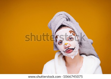 cute young girl with a towel on her head looks after herself, on her face a funny mask with a dog's face