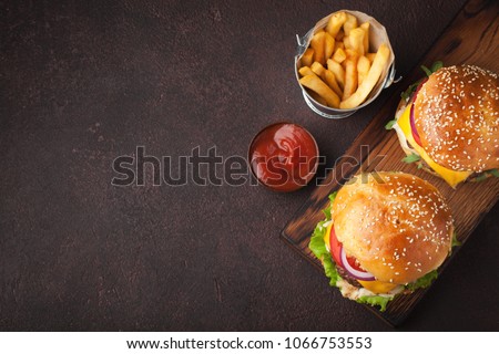 Tasty grilled home made burger with beef, tomato, cheese, cucumber and lettuce on a dark stone background with copy space. Top view. fast food and junk food concept
