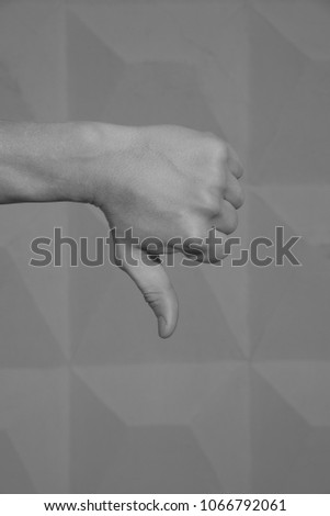 Hand of an adult male on grey background. Gesture of the hand - finger down, not acceptance, bad, refuse. black and white.