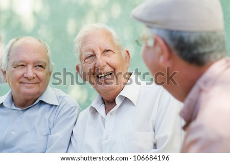 Active retirement, group of three old male friends talking and laughing on bench in public park Royalty-Free Stock Photo #106684196