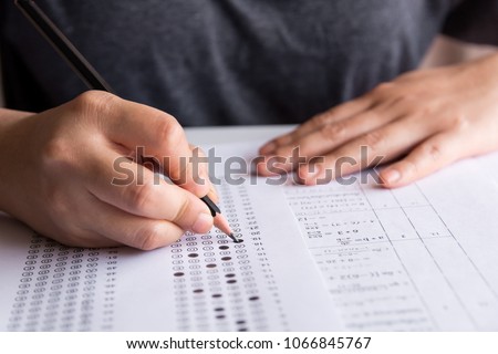 Students hand holding pencil writing selected choice on answer sheets and Mathematics question sheets. students testing doing examination. school exam  Royalty-Free Stock Photo #1066845767