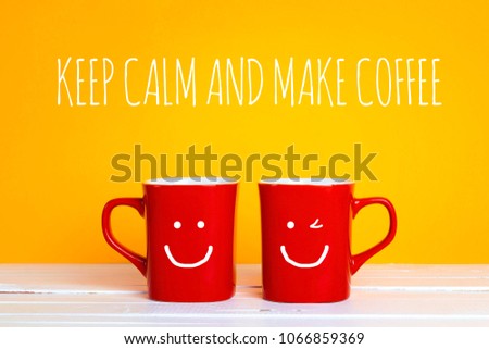 Two red coffee mugs with a smiling faces on a yellow background with the phrase Keep calm and make coffee. Happy coffee mugs.