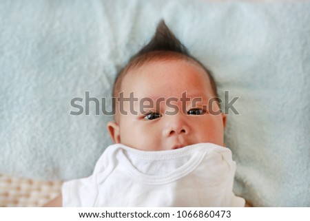 Adorable infant baby boy cover with cloth for dressing and lying on bed.