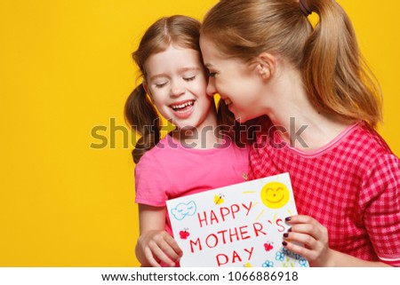 concept of mother's day. mom and child girl with picture postcard on colored background
