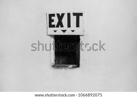 Exit sign over a small window on a white wall