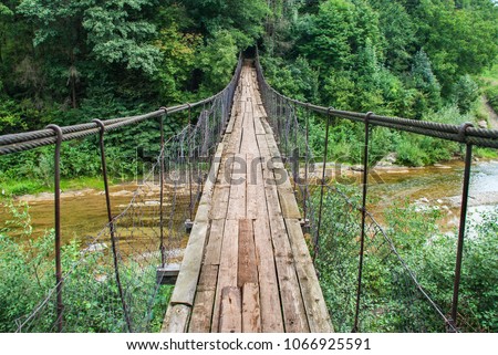 Suspension bridge, Crossing the river, ferriage in the woods Royalty-Free Stock Photo #1066925591