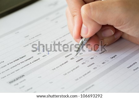 Hand with pen over blank check boxes in application form Royalty-Free Stock Photo #106693292
