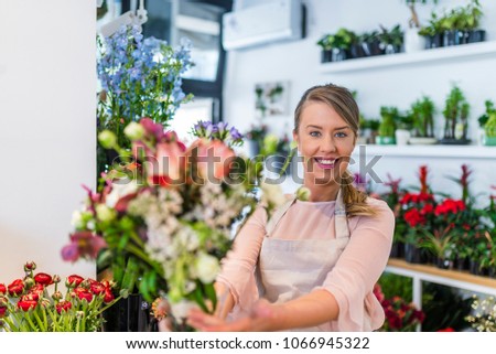 Young woman giving bouquet of flowers. Portrait of a happy florist offering and sale flowers at the counter in the florist shop. Florist giving beautiful flower bouquet to client